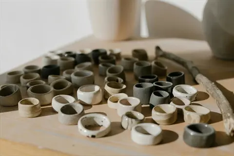 collection of ceramic bio rings in neutral tones (white, beige, gray, black) arranged on a wooden surface with a natural stick