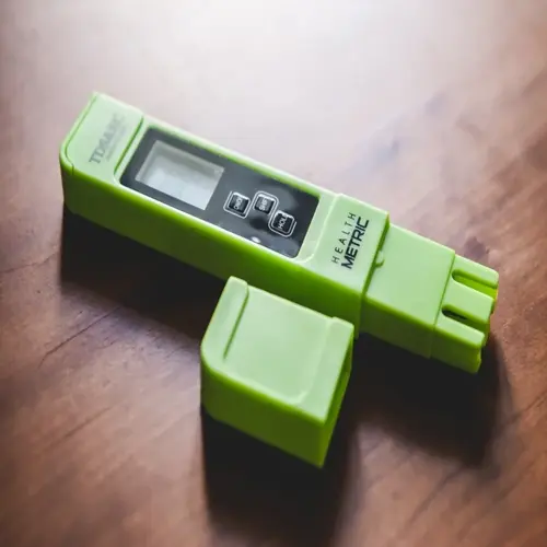 green tds meter for aquarium water testing on wooden surface