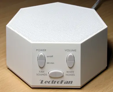 lectrofan white noise machine with control labels (power, volume, fan sounds, white noises) and circular adjustment buttons on wooden surface