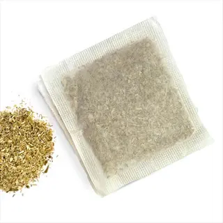single chamomile tea bag with loose dried chamomile flowers on white background
