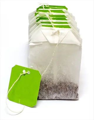 stack of green tea bags with bright green tags and string, isolated on white background